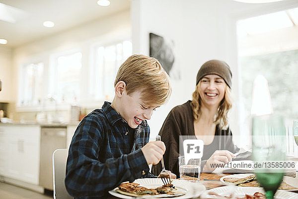 Mother and son eating pancake breakfast at table