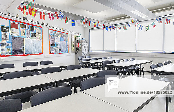 International flags hanging over desks in classroom