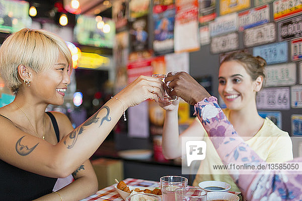 Young women friends taking alcohol shots in bar