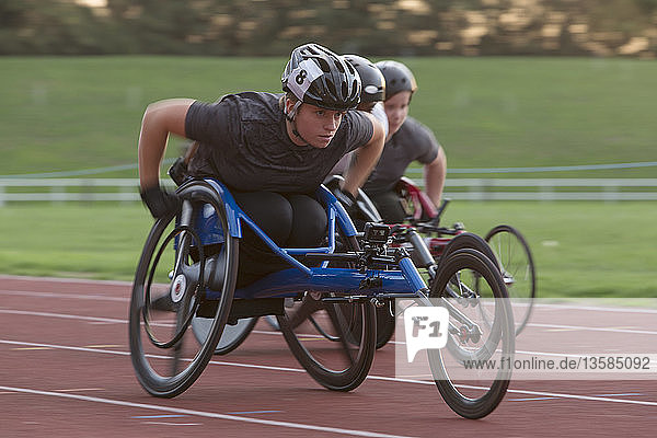 Entschlossene junge querschnittsgelähmte Athletin  die im Rollstuhlrennen über die Sportstrecke rast
