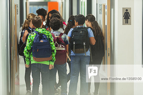 Junior high students with backpacks walking in school corridor