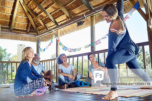 Female instructor demonstrating side angle pose in hut during yoga retreat
