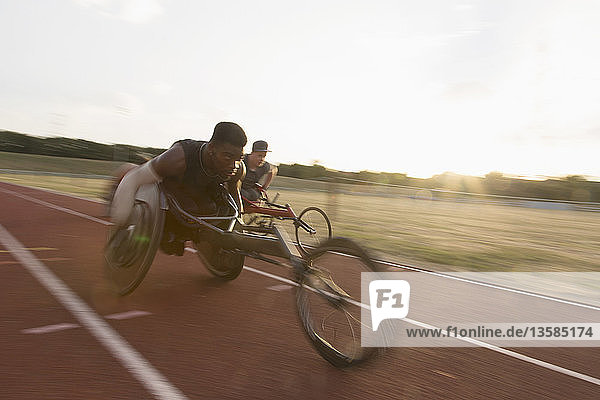 Entschlossener junger querschnittsgelähmter Sportler  der in einem Rollstuhlrennen über eine Sportstrecke rast