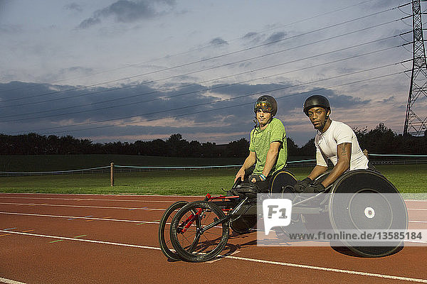 Porträt selbstbewusster querschnittsgelähmter Sportler beim Training für ein Rollstuhlrennen auf einer nächtlichen Sportbahn