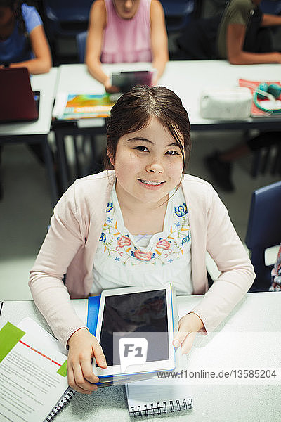 Portrait smiling  confident junior high school girl student using digital tablet in classroom