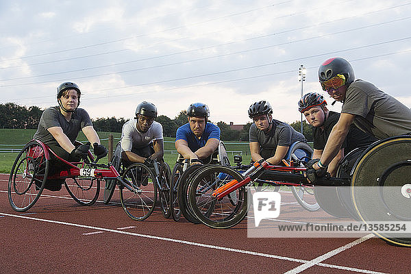 Porträt eines selbstbewussten  entschlossenen querschnittsgelähmten Sportlers  der auf einer Sportbahn für ein Rollstuhlrennen trainiert
