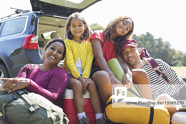 Porträt einer glücklichen Familie beim Zelten  Entladen des Autos