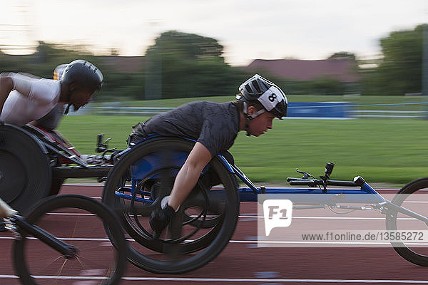 Determined paraplegic athletes speeding along sports track in wheelchair race