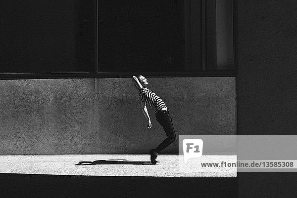 Junger Mann tanzt auf städtischem Bürgersteig