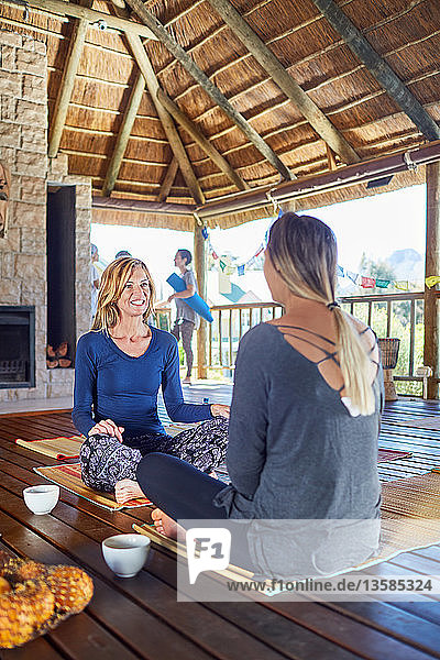 Frauen unterhalten sich und trinken Tee in einer Hütte während eines Yoga-Retreats