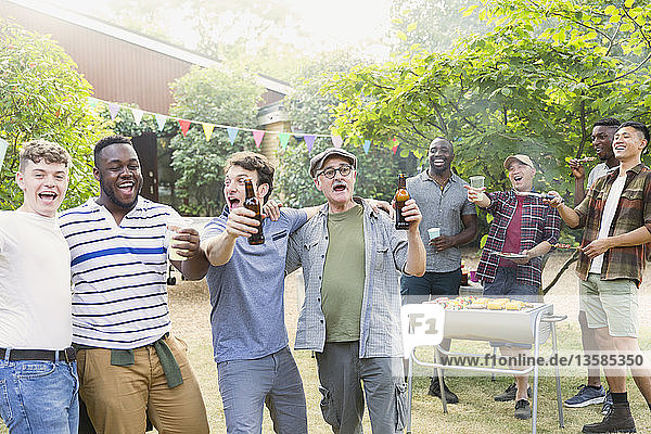 Fröhliche  ausgelassene männliche Freunde trinken Bier und singen beim Grillen im Hinterhof