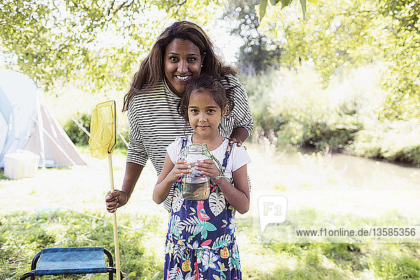Porträt glückliche Mutter und Tochter mit Fischernetz und Fisch im Glas auf dem Campingplatz