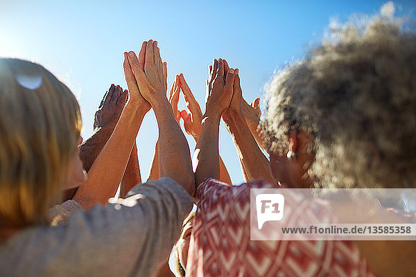 Gruppe mit im Kreis gefalteten Händen bei einem Yoga-Retreat