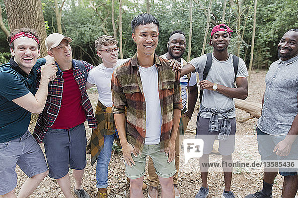 Porträt einer fröhlichen  unbekümmerten Männergruppe beim Wandern im Wald