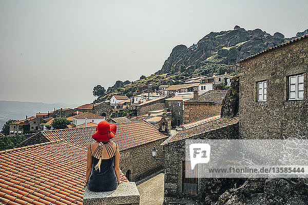 Woman in red hat looking at buildings on hillside  Monsanto  Portugal