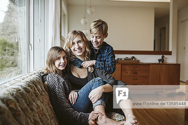 Portrait happy mother and children cuddling on living room sofa