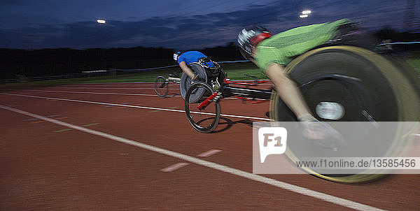 Paraplegic athletes speeding along sports track in wheelchair race at night