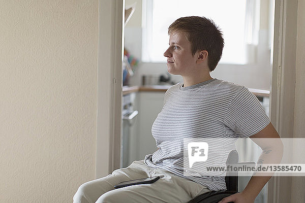 Thoughtful young woman in wheelchair at home