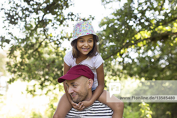 Father carrying daughter on shoulders in park