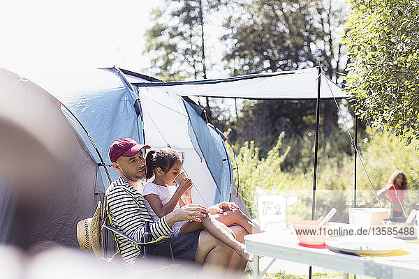 Father and daughter relaxing at campsite