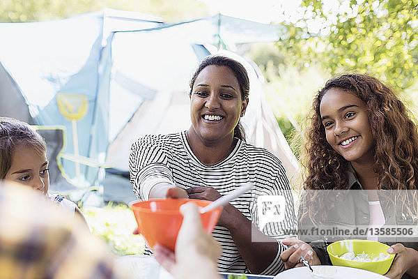 Smiling mother and daughters enjoying lunch at campsite