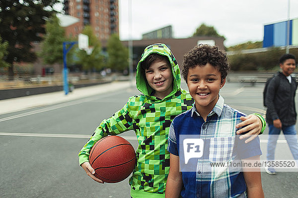 Porträt eines glücklichen Jungen in der Mittelstufe  der auf dem Schulhof Basketball spielt