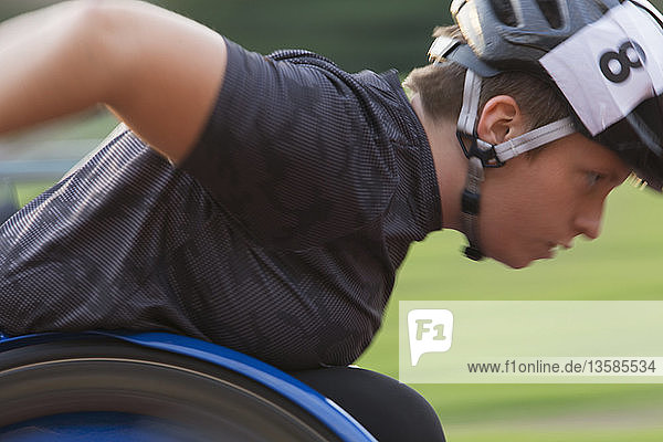 Determined female paraplegic athlete speeding along sports track during wheelchair race
