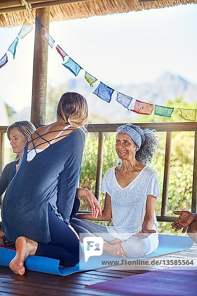 Weibliche Lehrerin im Gespräch mit einem Schüler in einer Hütte während eines Yoga-Retreats