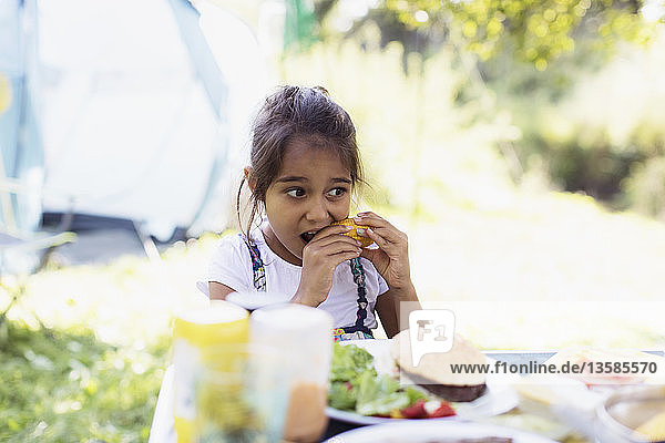 Girl eating corn on the cob at campsite