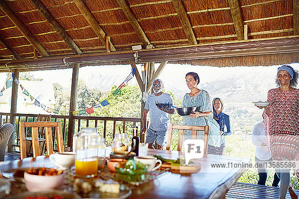 Friends carrying healthy food to table in hut during yoga retreat