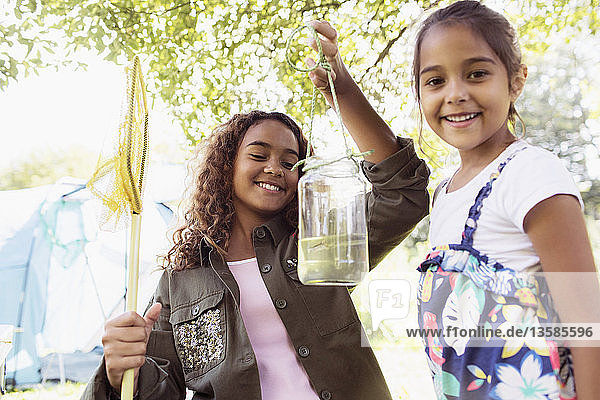 Portrait happy sisters catching fish in jar
