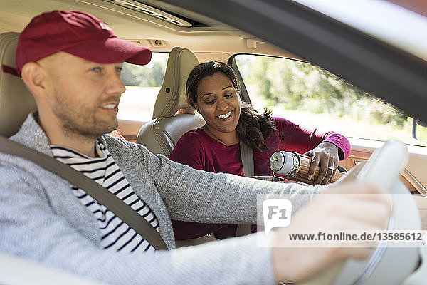 Couple drinking coffee in car on road trip