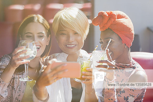 Junge Frauen Freunde trinken Cocktails und nehmen Selfie mit Smartphone in sonnigen Bar