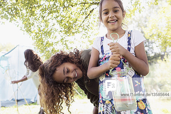 Portrait happy sisters catching fish in jar