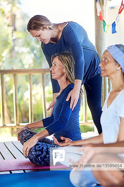 Eine Lehrerin richtet die Schultern eines Schülers während eines Yoga-Kurses aus