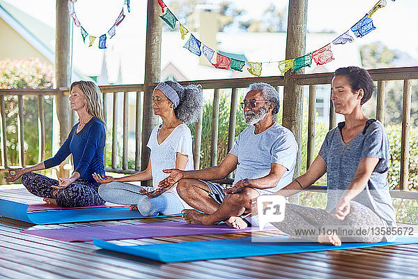 Gelassene Menschen meditieren in einer Hütte während eines Yoga-Retreats