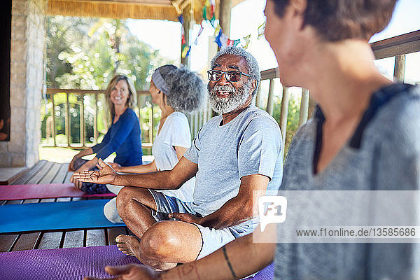 Älterer Mann im Gespräch mit einer Frau in einer Hütte während eines Yoga-Retreats