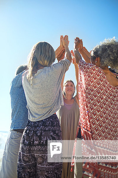 Im Kreis stehende Gruppe mit erhobenen Armen während eines Yoga-Retreats