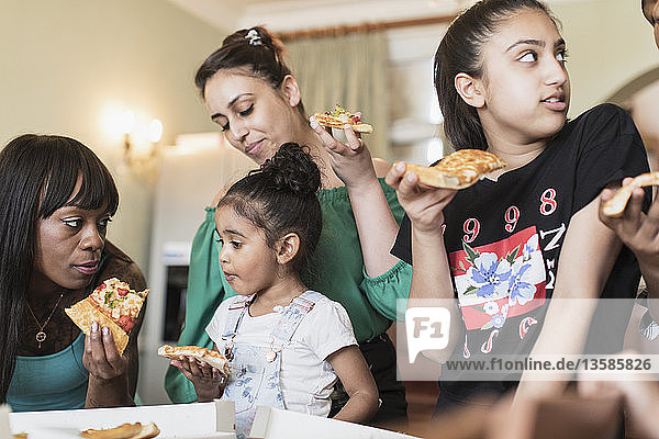 Lesbian couple and daughters eating pizza