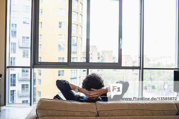 Mann entspannt sich auf dem Sofa einer städtischen Wohnung