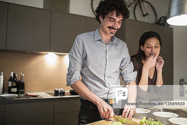 Ehepaar schneidet Gemüse und bereitet das Abendessen in der Wohnküche vor