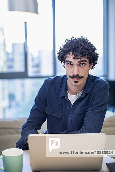Porträt selbstbewusster Mann bei der Arbeit am Laptop