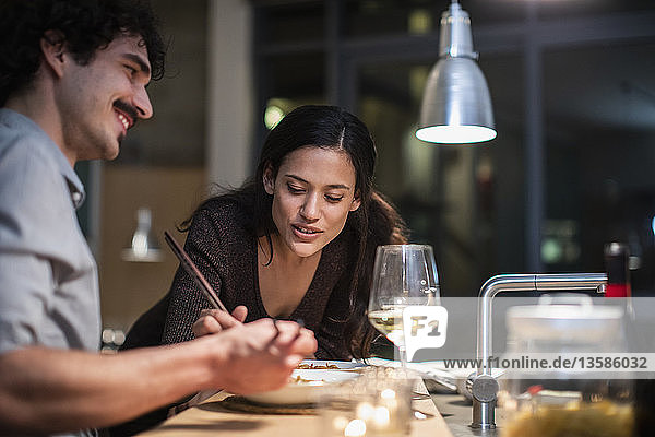 Paar isst Abendessen mit Stäbchen und trinkt Weißwein in der Wohnküche