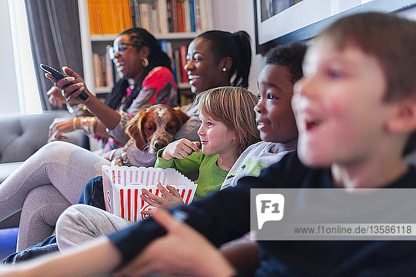 Multiethnische Familie schaut einen Film und isst Popcorn