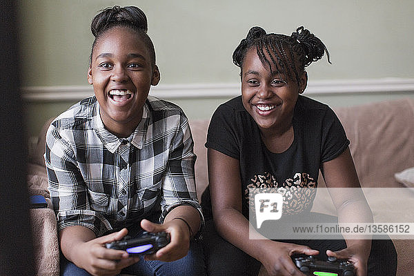 Tween Freundinnen spielen ein Videospiel auf dem Wohnzimmersofa