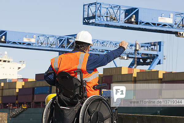 Transportingenieur im Rollstuhl gibt Anweisungen zu den Schiffscontainern im Verschiffungshafen