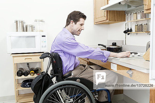 Ein Mann im Rollstuhl mit einer Rückenmarksverletzung stellt die Hitze an einem zugänglichen Ofen ein