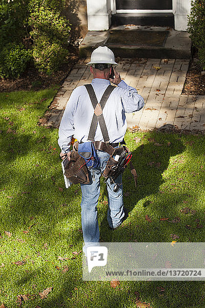 Cable installer on cell phone preparing to enter home for installation