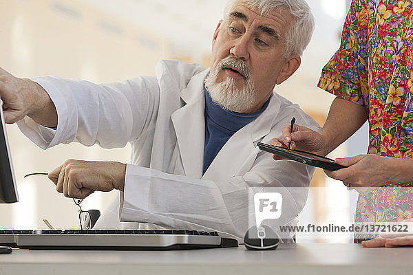 Doctor and nurse in conference with computer and tablet