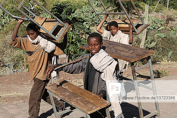 Boys carrying schooldesks
